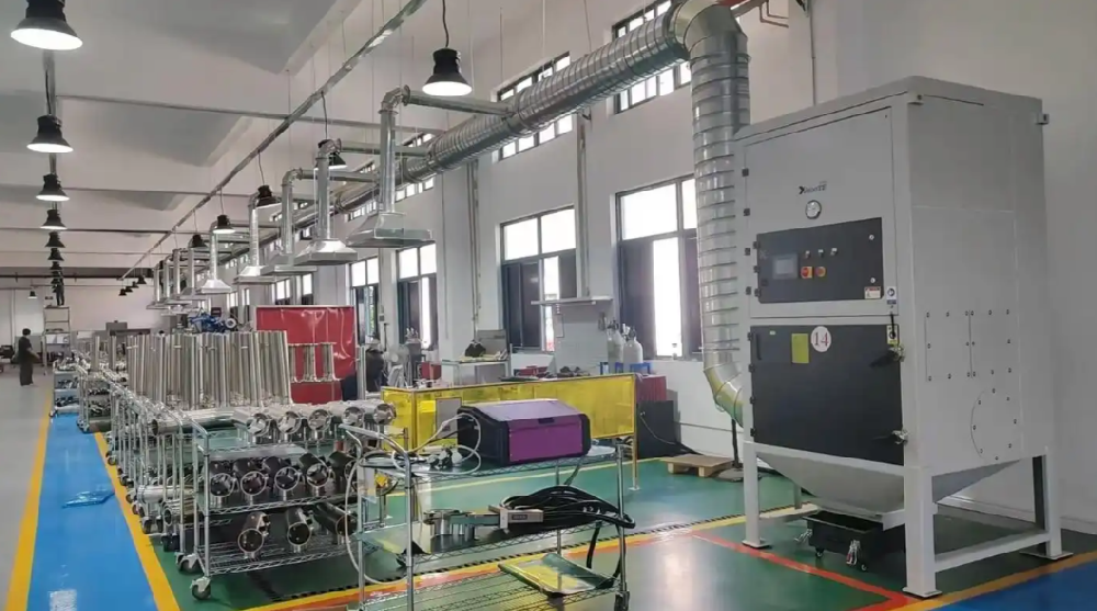 工人操作小型布袋除塵器進行焊接煙塵收集的車間實景